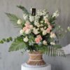 This stunning bouquet of flowers in a small wicker stool is the perfect way to brighten up any room. Soothing to the eyes, the arrangement features a variety of blooms in pastel shades. The flowers are arranged in a rustic wicker base, which adds to the overall charm of the bouquet. This arrangement is perfect for any occasion, whether you're looking for a gift for a loved one, a centerpiece for a special event, or simply want to add a touch of beauty to your home décor.