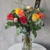 A lovely glass vase filled with a beautiful arrangement of vibrant roses in a variety of colors. This centerpiece is perfect for any occasion, from a birthday to an anniversary to a simple day of appreciation.